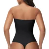 Rear view of a model wearing a black front closure body shaper, showcasing the low-back cut and seamless thong styling.